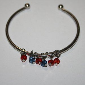 Silver cuff bracelet with red and blue charms